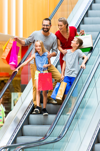 Family in shopping mall on escalators with bags - Photo, Image