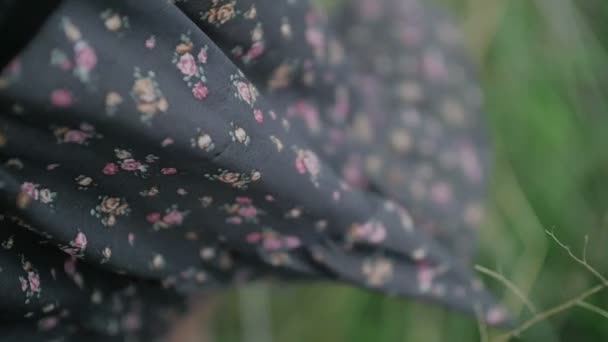 donkere jurk met de bloemen print waait door wind gekleed door mooie vrouw dicht omhoog shot groene achtergrond - Video