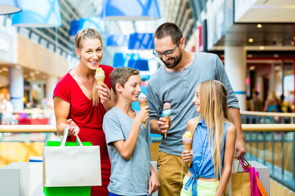 Famille manger de la glace dans le centre commercial avec des sacs
 - Photo, image
