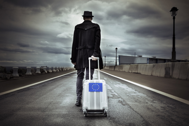 νεαρός άνδρας με μια συνεχιζόμενη βαλίτσα με μια ευρωπαϊκή σημαία - Φωτογραφία, εικόνα