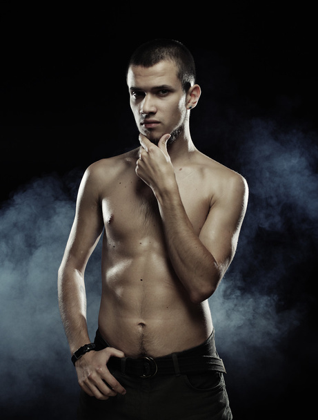 Portrait of a muscular male model against dark  background with  - Foto, Imagem