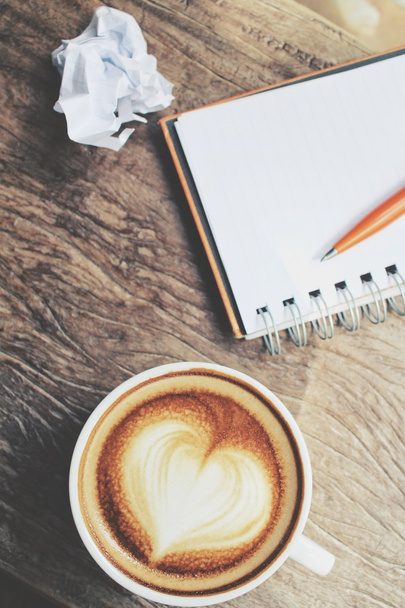 Пустой блокнот и ручка с кофе латте на рабочем столе
 - Фото, изображение