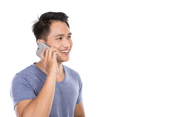 Azjatycki młody człowiek mówi na telefon na białym tle - Zdjęcie, obraz