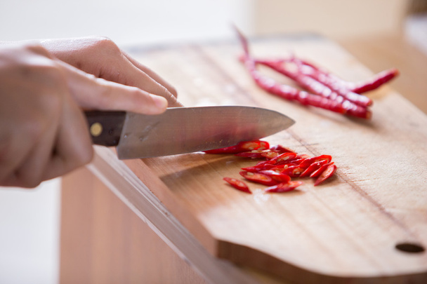 Hand slicing chilli pepper  on wooden background. - Fotoğraf, Görsel