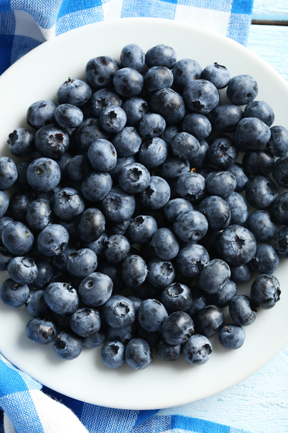 Blueberries in plate on wooden background - Foto, afbeelding