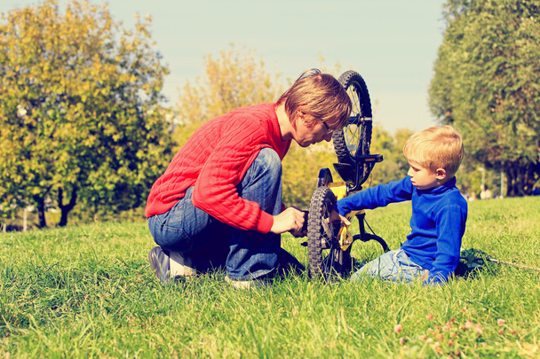 isä ja poika korjaus pyörä ulkona
 - Valokuva, kuva