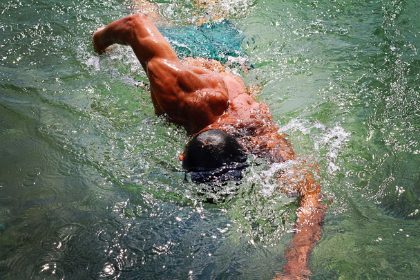 Сильный мускулистый человек, плавающий в морском океане. Активный летний отдых. Спорт, концепция здорового образа жизни
 - Фото, изображение
