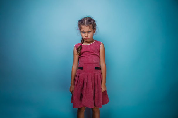 Girl seven years old, European-looking brunette in a pink dress her head and frowned on a gray background, bad mood, anger - Fotó, kép