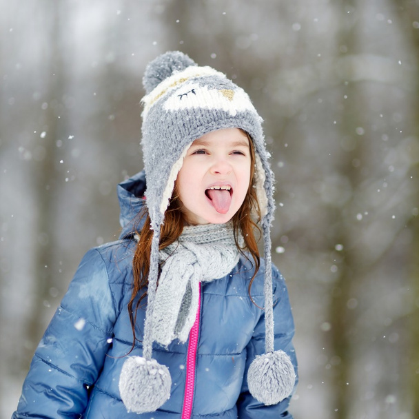 girl catching snowflakes in winter park - Foto, Bild