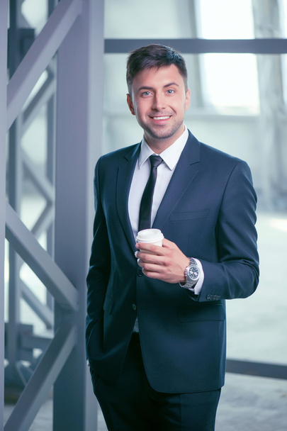 Attractive young man in suit is enjoying hot drink - Фото, изображение