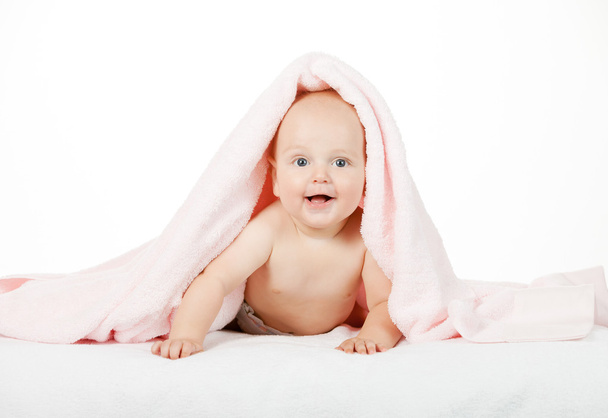Caucasian baby boy covered with pink towel joyfully smiles at ca - Foto, imagen