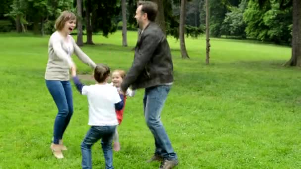 family (middle couple in love, cute girl and small boy) dance in circle in the park - Footage, Video