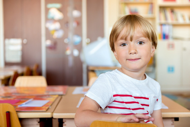 Indoor portrait of a cute little boy in a classroom - Zdjęcie, obraz