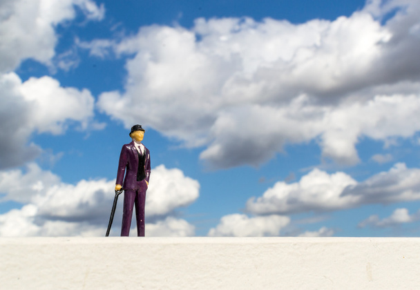 Üzleti ember miniatűr modell és a felhős ég - Fotó, kép