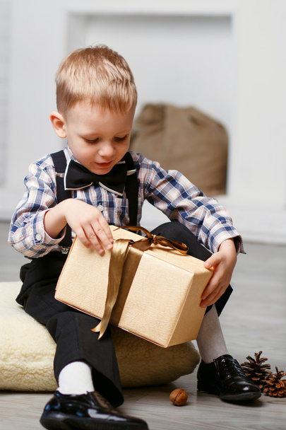 Mały chłopiec otwierając prezent w dekoracje na Boże Narodzenie czeka - Zdjęcie, obraz