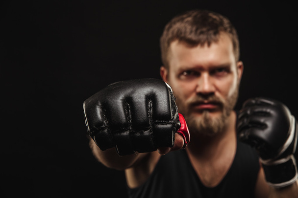 Athletic bearded boxer with gloves on a dark background - Foto, Bild