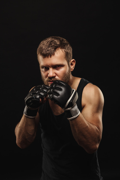 Athletic bearded boxer with gloves on a dark background - 写真・画像