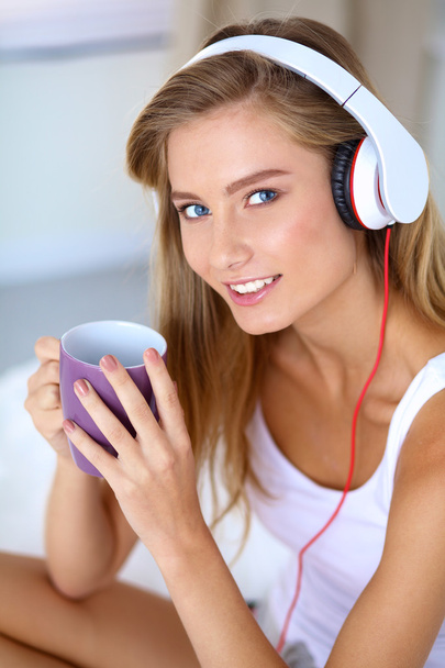 Portrait of beautiful woman in morning listening music sitting on bed at home - Фото, изображение