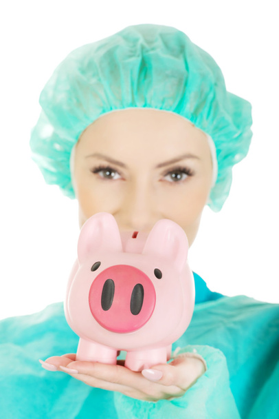 Female doctor with pink piggy bank. - Foto, afbeelding