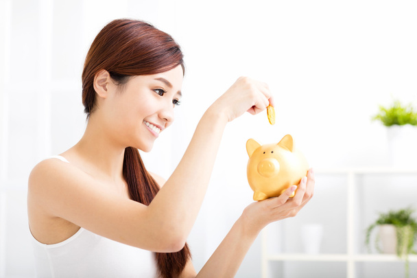 Happy young woman saving money in the piggy bank - Photo, Image