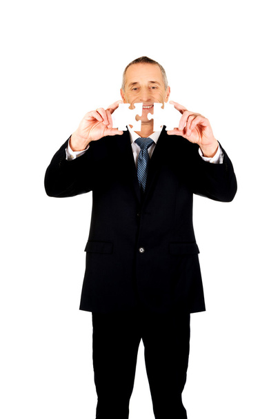 Businessman trying to connect puzzle pieces. - Photo, Image
