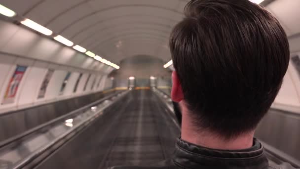 junger gutaussehender Hipster fährt auf der Rolltreppe in der U-Bahn - von hinten erschossen - Filmmaterial, Video