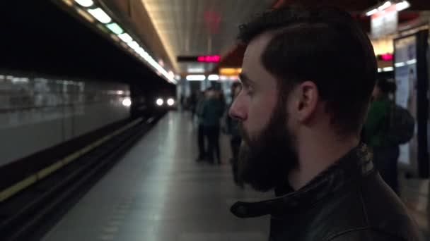 mladý pohledný hipster muž čeká na metro a rozhlédne se - přijíždějící metro - Záběry, video