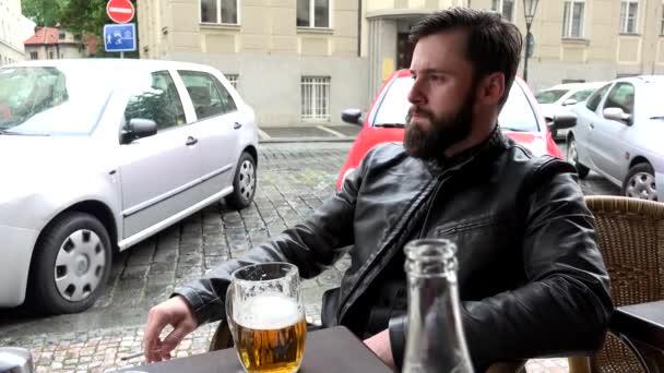 jovem homem hipster bonito sentado no restaurante (assentos ao ar livre) e fumando - rua (carros estacionados) - cerveja
 - Filmagem, Vídeo