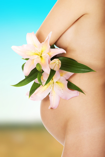Pregnant woman holding a lily flower - Фото, зображення