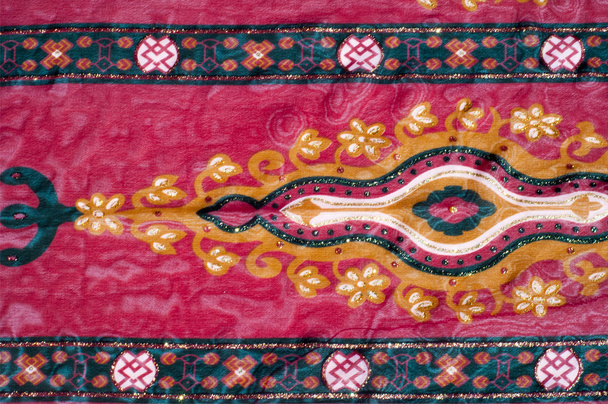 Текстурная шелковая ткань с красным узором. Красная ткань с валлийскими грушами сфотографирована крупным планом. Индийский цветочный узор с огурцами на натуральной шелковой ткани
. - Фото, изображение