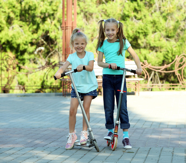 Small girls riding on scooters - Foto, Imagen