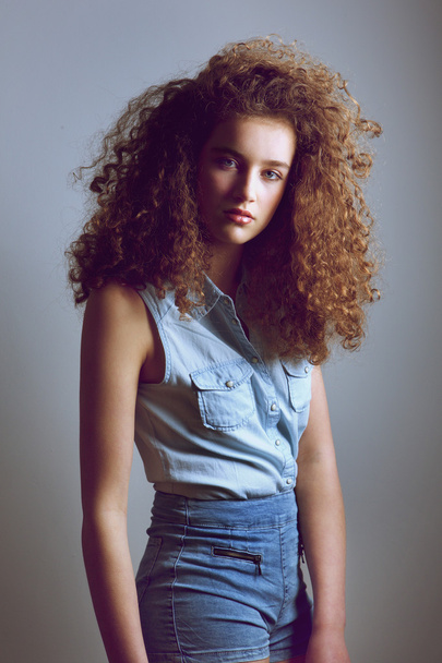 Teen female fashion model with curly hairstyle in denim shirt - Foto, Imagem