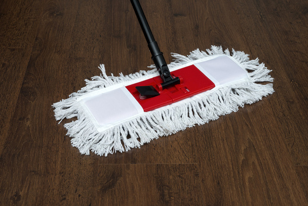 De mop op de parketvloer tijdens het reinigen - Foto, afbeelding