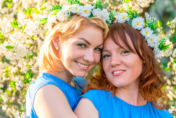 two girlfriends with wreaths on the head near the blossoming che - Foto, imagen