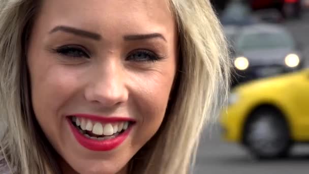 若い魅力的なブロンドの女性は、カメラ - 都市の車と都市ストリート - クローズ アップする笑顔します。 - 映像、動画