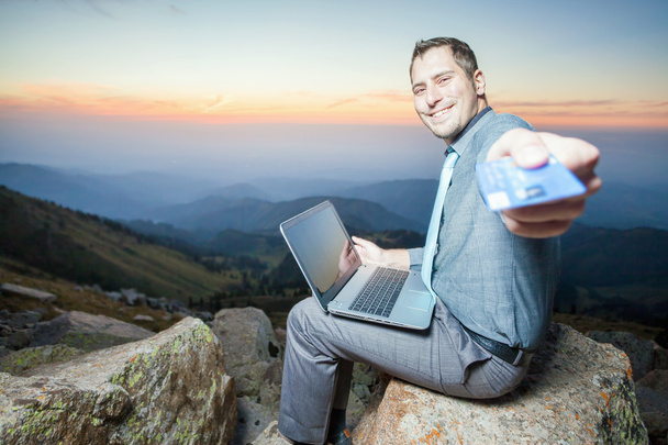 successful businessman on top of mountain, using a laptop - Foto, afbeelding