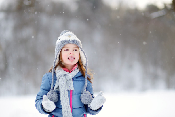 girl catching snowflakes in winter park - Valokuva, kuva