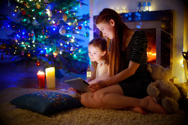 Mother and daughter using a tablet by a fireplace - Foto, Imagem