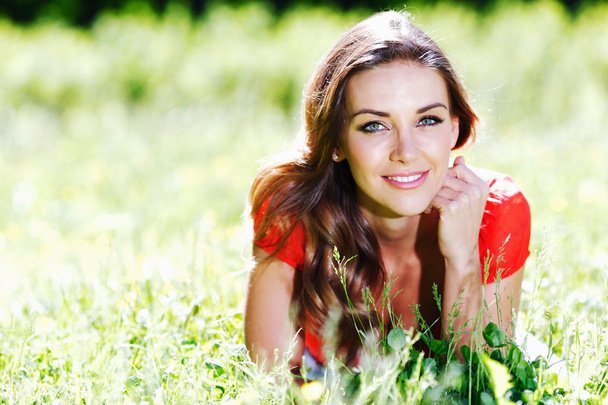 young woman in red dress lying on grass - Foto, Bild