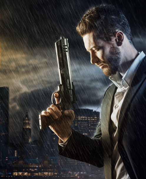 agent under pouring rain holding a gun - Foto, imagen