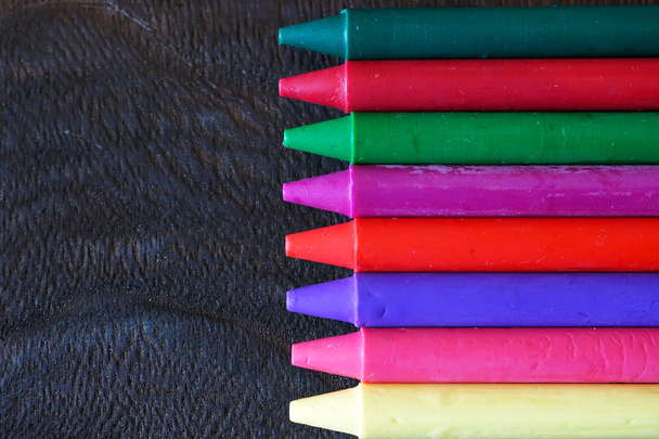 színes olaj pasztell ceruzák, egy fából készült fekete asztal - Fotó, kép