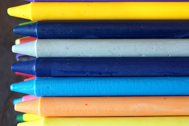 Цветные масляные пастельные карандаши на деревянном черном столе
 - Фото, изображение