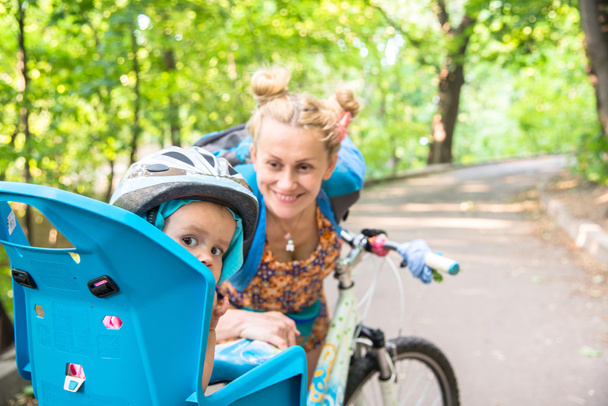 Mom on a bike with a small child, who wore a bicycle helmet and  - Foto, Imagem