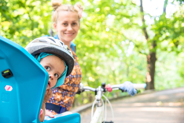 Mom on a bike with a small child, who wore a bicycle helmet and  - Φωτογραφία, εικόνα