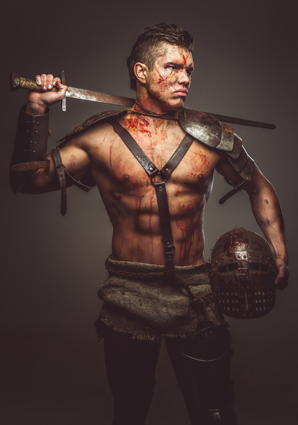 Muscular shirtless gladiator holding helmet - Фото, изображение