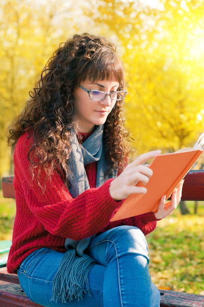 Молода жінка читає книгу в осінньому парку
 - Фото, зображення