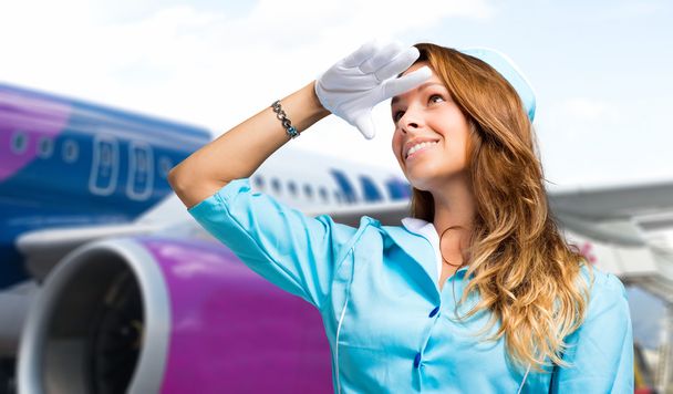 smiling stewardess in front of plane - Valokuva, kuva