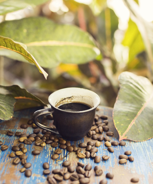 Šálek kávy a kávových zrn na dřevěném stole - Fotografie, Obrázek