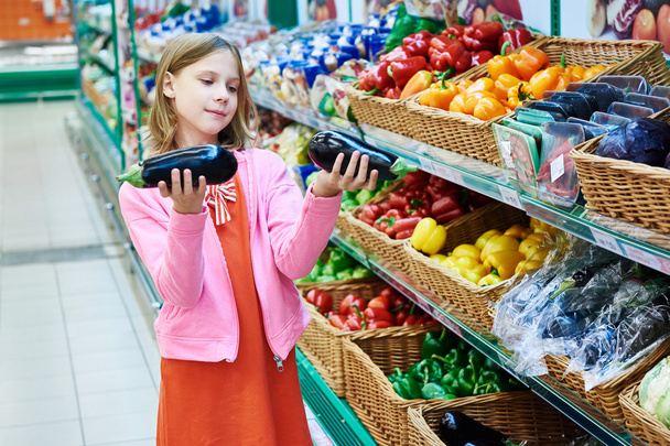 Girl chooses eggplants in supermarket - Foto, Imagen