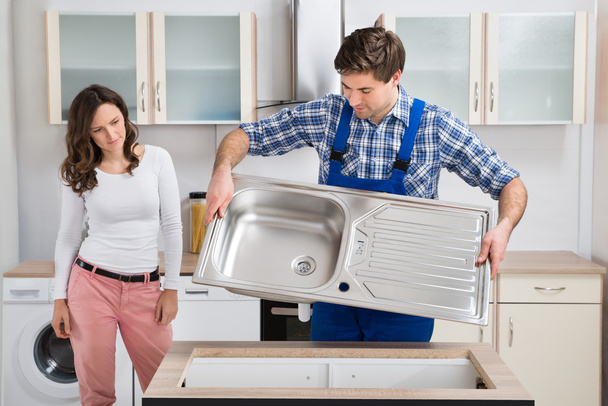 Woman Looking At Worker Carrying Kitchen Sink - Foto, immagini
